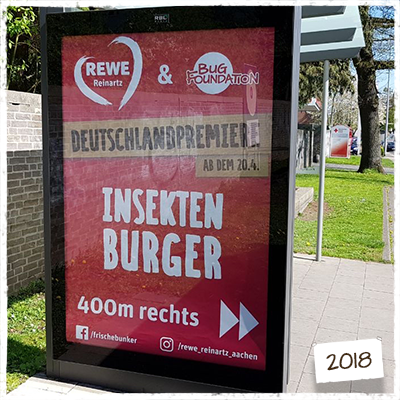 rotes Plakat von Rewe an einer Bushaltestelle